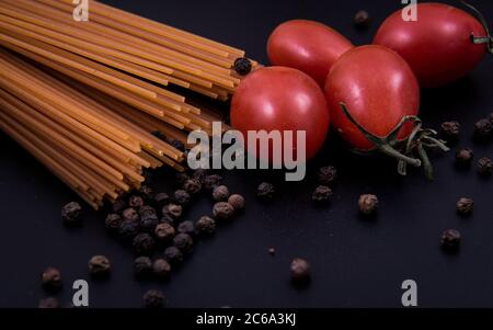 Pasta in Form und Pasta in Form. Pasta in verschiedenen Formen und Farben mit Tomaten und Pfefferkörnern. Stockfoto