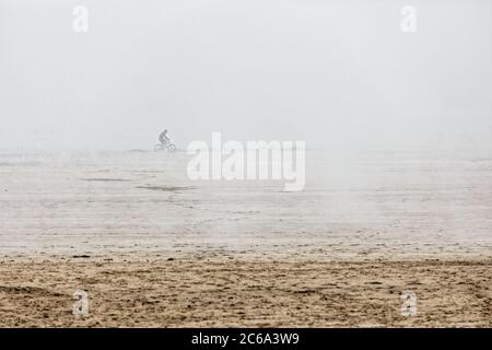 Im Bild: Ein eineinesischer Radfahrer fährt in der niedrigen Wolke in Swansea Bay, Wales, Großbritannien. Mittwoch 20 Mai 2020 Re: Eine niedrige Wolke hat das Meer und den Strand von bedeckt Stockfoto