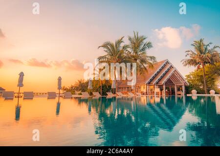 Wunderschöner Pool und Sonnenuntergang. Luxuriöse tropische Strandlandschaft, Liegestühle und Liegen und Wasserspiegelung. Toller Urlaub, Sommerurlaub Stockfoto