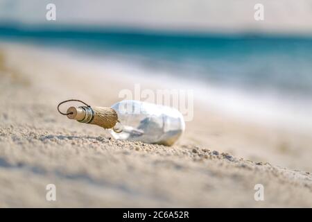 Flasche mit einer Nachricht, Wellen des Meeres planschen an der ruhigen Küste, an der Küste. Exotisches Castaway-Konzept. Flasche mit einer Nachricht für Hilfe. Strand. Stockfoto