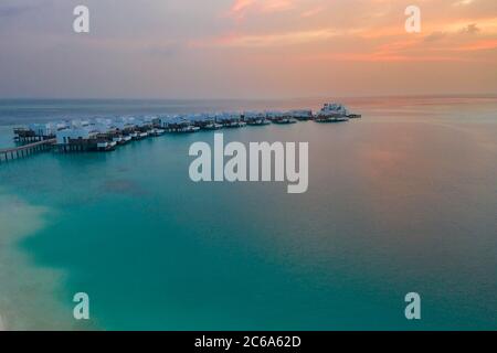 Luftaufnahme der Malediven Insel Sonnenuntergang. Wasser Bungalows Resort am Strand der Inseln. Luftaufnahme Malediven. Wunderschöne Sonnenuntergangslandschaft, Luxus-Resort und bunten Himmel Stockfoto