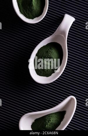 Natürliche grüne Chlorella oder Spirulina Pulver in drei unterschiedlich geformten weißen Porzellanschalen. Gesunde Superfood Ernährung und Diät-Konzept. Stylisches B Stockfoto