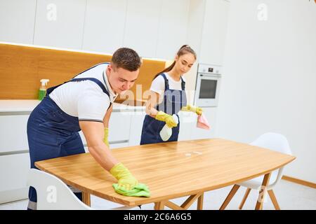Zwei junge Putzfrauen in Uniform arbeiten effektiv und schnell in der Küche zusammen Stockfoto
