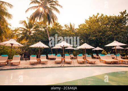 Wunderschöner tropischer Strand im Resort Hotel Island. Pool mit Stühlen, Liegestuhl unter Sonnenschirm und Palmen. Sommerurlaub, Urlaubsreisekonzept Stockfoto