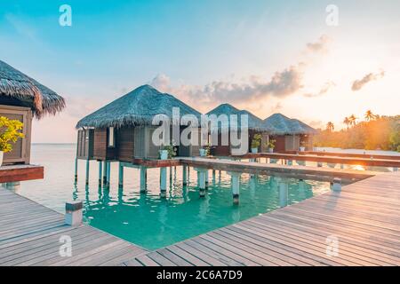 Sonnenuntergang auf den Malediven Insel, Luxus Water Villas Resort und hölzernen Pier. Schönen Himmel und Wolken und Strand Hintergrund für Sommer Urlaub Stockfoto