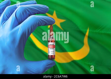 Mauretanien Flagge mit Coronavirus Covid-19 Konzept. Arzt mit blauen Schutzhandschuhen mit einer Impfstoffflasche. Epidemic Virus, Cov-19, Corona Stockfoto