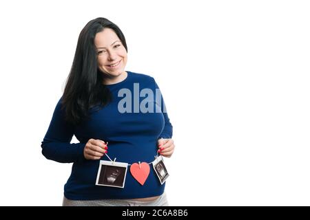 Lächelnde schwangere Frau hält String mit Ultraschall-Bilder und roten Herzen als Liebe Konzept isoliert auf weißem Hintergrund Copyspace Stockfoto