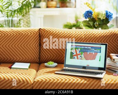 Nahaufnahme auf Laptop mit fremdsprachiger Online-Schule auf einer Couch im modernen Zuhause an sonnigen Tag. Stockfoto