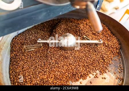 Frisch geröstete Kaffeebohnen aus einem großen Bräter im Kühlzylinder. Bewegungsunschärfe auf Bohnen. Stockfoto