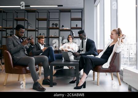 afroamerikanische und kaukasische Geschäftspartner trafen sich, um über neues Projekt in modernen bequemen Büro zu sprechen Stockfoto