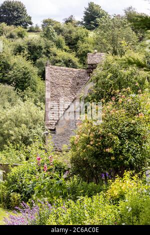 Ein Blick auf die alte Steindovecote (um 1600 n. Chr.), die man in einem Sommergarten im Cotswold-Dorf Naunton, Gloucestershire, UK, sieht Stockfoto