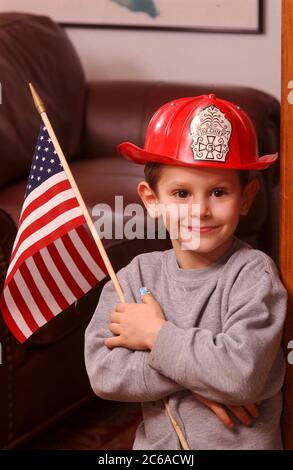 Austin, Texas, USA, 31. Januar 2002: Robin David Daemmrich, 5 Jahre, posiert mit einem Feuerwehrhelm und einer amerikanischen Flagge während des Spiels. Er sagt, er will ein tapferer Feuerwehrmann sein, wenn er groß ist. ©Bob Daemmrich Stockfoto