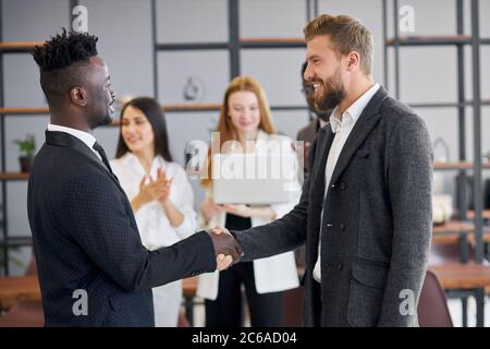 afroamerikanisch und kaukasisch nach interracial Business Meeting schütteln Sie die Hände. Glückliches und positives Ende der Verhandlungen Stockfoto