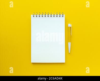 Weißes leeres Notizbuch mit Stift darauf. Pädagogisches Konzept in gelben und weißen Farben. Stock Foto. Stockfoto