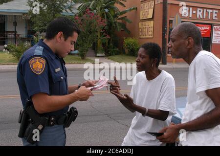 San Antonio, Texas 7.-8. August 2003: Polizeibeamte im Süden von San Antonio. Der hispanische Polizist Joe Rios spricht mit zwei schwarzen Bewohnern, die angehalten und durchsucht wurden, als eine Rauchpfeife in ihrem Auto gefunden wurde. ©Bob Daemmrich/The Image Works Stockfoto