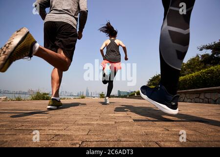 Drei junge asiatische Erwachsene joggen im Freien, hinten und in der unteren Winkel Ansicht
