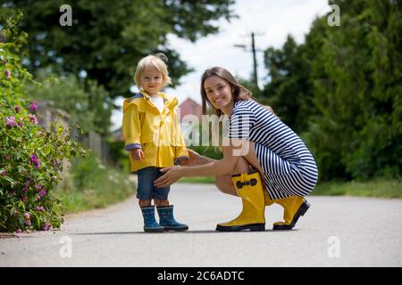 Mutter und Kleinkind Kind, Junge, spielen im Regen, Stiefel und Regenmäntel tragen Stockfoto