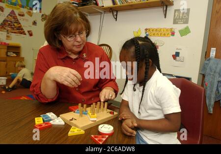 Gun Barrel City, Texas, USA, 9. September 2003: Neunjährige afroamerikanische Schülerin mit Down-Syndrom arbeitet in einer öffentlichen Schule mit sprach- und Hörspezialistin, während sie Manipulationen einsetzt, um das Zählen zu üben und Formen und Farben zu lernen. MODELLVERSION SP63 (Schüler) und SP69 (Lehrer). ©Bob Daemmrich Stockfoto