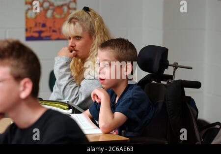 Mabank, Texas, USA, 10. September 2003: Ein 12-jähriger Junge mit Zerebralparese und Lernbehinderung sitzt in einem regulären Klassenzimmer der 7. Klasse in einer öffentlichen Mittelschule. Er hat den ganzen Schultag über einen Vollzeitassistenten. MODELLVERSION SP-71 (Junge) und SP-72 (AIDE). ©Bob Daemmrich Stockfoto