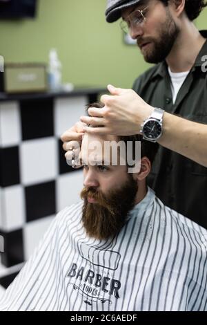 Portrait von attraktiven jungen Mann immer trendy Frisur. Männliche Friseur Dienst Client, machen Haarschnitt mit Metallschere Stockfoto