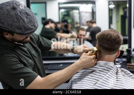 Schöner bärtiger Mann bekommt neue Frisur mit Rasiermesser von Friseur im Friseurladen Stockfoto