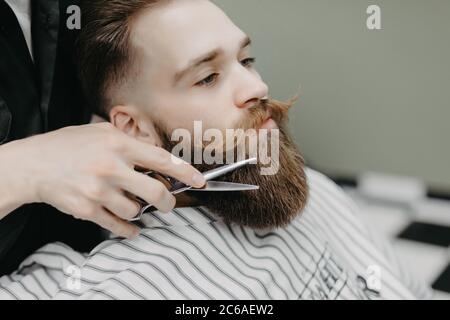 Bart stylen und schneiden. Nahaufnahme eines beschnittenen Fotos mit einem roten Bart. Werbe- und Friseurgeschäft Konzept Stockfoto