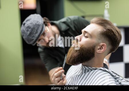 Bart stylen und schneiden. Nahaufnahme eines beschnittenen Fotos mit einem roten Bart. Werbe- und Friseurgeschäft Konzept Stockfoto