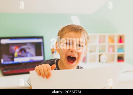 Der Junge müde von Online-Unterricht und laut weinen Stockfoto