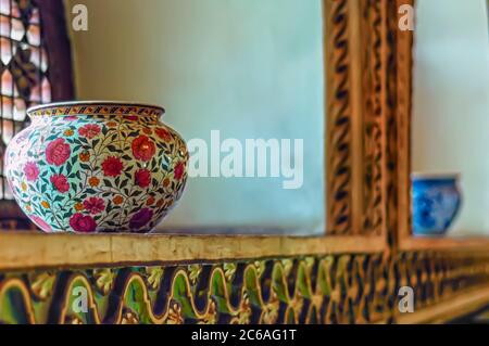 Eine antike Keramikvase, die auf einem Vorsprung neben einem Fenster im Chowmahalla Palace, Hyderabad, Telangana, Indien, sitzt. Stockfoto