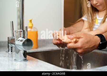 Vater und Tochter waschen sich die Hände über dem Waschbecken in einer Küche Stockfoto
