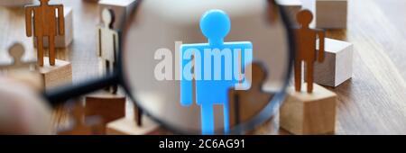 Suche nach vermisster Person in Menge von Spielzeugfiguren mit Lupe Stockfoto