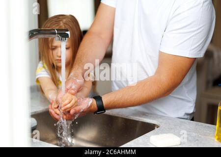 Vater und Tochter waschen sich die Hände über dem Waschbecken in einer Küche Stockfoto