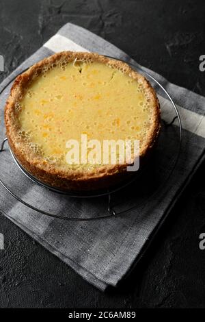 Gesundes Dessert im Hygge-Stil. Zitronenkuchen mit Vollkornkornmehl-Haferflocken auf Kühlregal und Leinentuch auf schwarzem Hintergrund, High-Angle-View-Kopierfläche Stockfoto