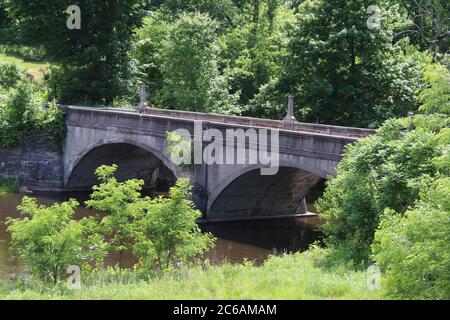 Eine alte Bogenbrücke über einen Fluss auf dem Land Stockfoto