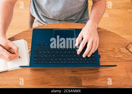 Aufnahme des Home Office-Desktops mit Telearbeit mit männlichen Händen auf einem modernen Laptop Stockfoto
