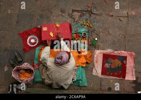 Brahmin bereitet Paste vor, um Tilaka-Markierungen an Gläubige neben dem Eingang zum Dakshinkali-Tempel in der Nähe von Kathmandu, Nepal, anzuwenden. Einer der wichtigsten Hindu-Tempel in Nepal, der der Göttin Kali gewidmet ist, ist für seine Tieropfer bekannt, die im Hauptheiligtum stattfinden. Stockfoto