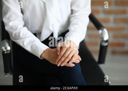 Frau sitzt auf einem Stuhl mit Händen zusammengeklemmt. Stockfoto