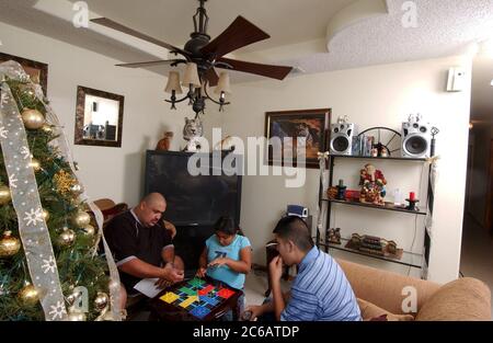 Monte Alto, Texas, USA, Dezember 11 2004: The Villalpando Family in the living room of their bescheidene 3-Schlafzimmer, one bathroom House purchased by Proyecto Azteca, ein Wohnungsbauhilfeprogramm, bei dem Familien ehrenamtliche Zeit im Austausch für den Kauf eines Billighauses beisteuern müssen. Modell Veröffentlicht ©Bob Daemmrich Stockfoto