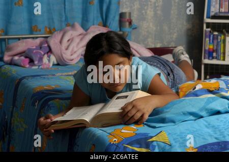 Monte Alto, Texas, USA, Dezember 11 2004: Hispanisches neunjähriges Mädchen liest ein Wörterbuch in ihrem Schlafzimmer Model erschien ©Bob Daemmrich Stockfoto