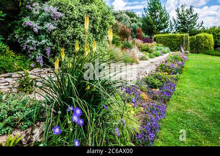 Terrassenförmig angelegte krautige Grenzen in einem abfallenden Landgarten. Stockfoto