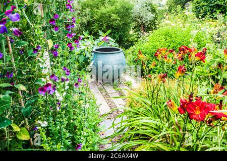 Ein großer Pflanzenbehälter, der als Brennpunkt in einem Sommergarten verwendet wird. Stockfoto