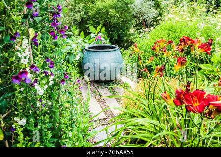 Ein großer Pflanzenbehälter, der als Brennpunkt in einem Sommergarten verwendet wird. Stockfoto