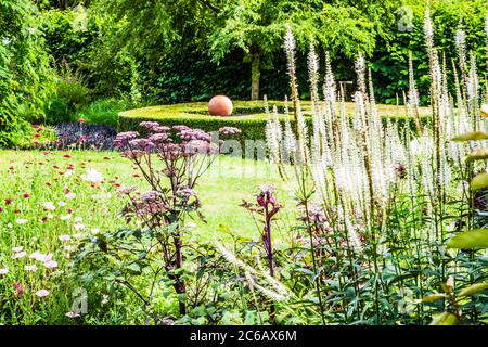 Ein großer Pflanzenbehälter, der als Brennpunkt in einem Sommergarten verwendet wird. Stockfoto