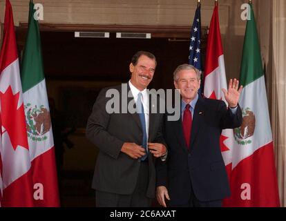 Waco Texas USA, 23. März 2005: USA Präsident George W. Bush winkt, während er den mexikanischen Präsidenten Vicente Fox bei Fox begrüßt, der in der Armstrong Browning Library an der Baylor University zu einem Gipfeltreffen zusammen mit dem kanadischen Premierminister Paul Martin eintrifft. (Poolfoto) ©Bob Daemmrich Stockfoto