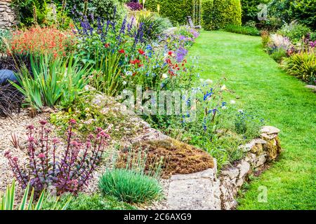 Terrassenförmig angelegte krautige Grenzen in einem abfallenden Landgarten. Stockfoto