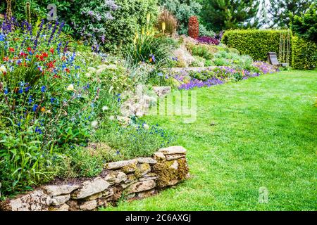 Terrassenförmig angelegte krautige Grenzen in einem abfallenden Landgarten. Stockfoto