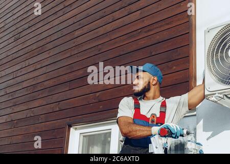 Reparaturman in Uniform Installation der Außeneinheit der Klimaanlage Stockfoto