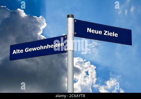 Straßenschild vor wolkenverhakter Luft, das die Wahl zwischen ‘Alten Gewöhnen’ und ‘Neuen Zielen’ auf Deutsch darstellt Stockfoto