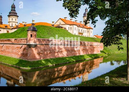 Nesvizh, Weißrussland. Blick auf eine schöne mittelalterliche Burg an einem Sommertag. Eine alte Festung spiegelt sich im Wasser. Stockfoto