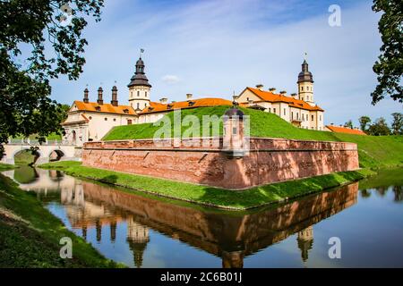 Nesvizh, Weißrussland. Blick auf eine schöne mittelalterliche Burg an einem Sommertag. Eine alte Festung spiegelt sich im Wasser. Stockfoto